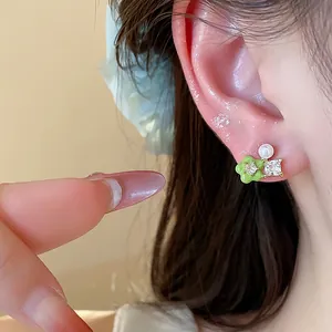 Close-up detail of 18k gold plated flower earring with green enamel and zircon