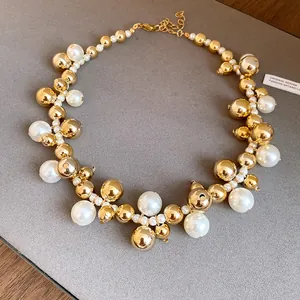 Vue détaillée d'un collier vintage avec des perles dorées brillantes et des perles d'imitation.