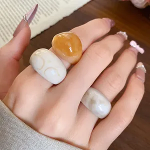 Détail macro de trois bagues en résine minimalistes en ambre et blanc marbré