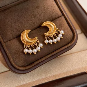 Vintage gold crescent moon earrings with dangling pearl tassels in a brown jewelry box.