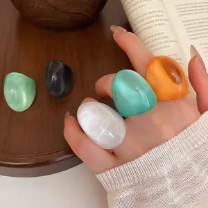 Detailed macro view of vibrant chunky resin rings in various candy colors worn on a hand