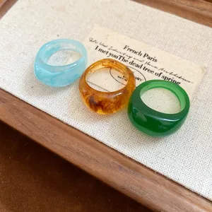Détail de trois bagues en résine colorée avec des textures marbrées et unies