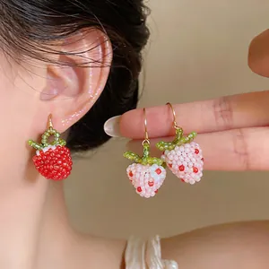 Macro detail of sweet handmade glass bead strawberry earrings in red and pink hues
