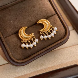 Detailed view of vintage golden crescent earrings with elegant pearl tassel charms.