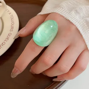 Detail view of a chunky mint green candy resin ring on a manicured model finger