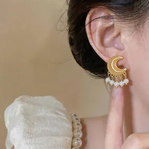 Close-up of vintage gold crescent moon earrings with pearl fringe tassels on model's ear