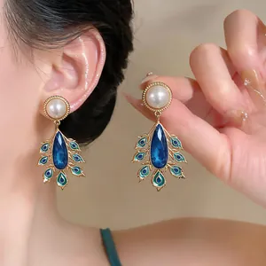 Detailansicht von Vintage-Palast-Ohrringen mit blauen Kristalltropfen und weißen Perlen.