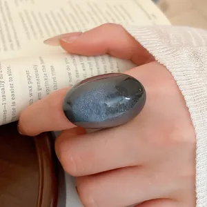 Detailed macro shot of a large grey resin oval ring worn on a hand