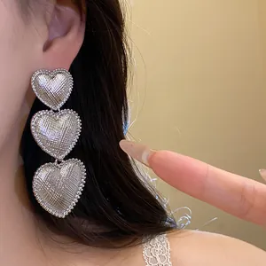 Macro detail view of elegant textured silver triple heart drop earrings for women
