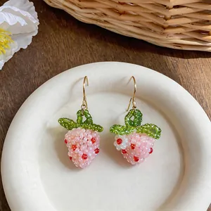 A high-quality detail view of handmade beaded strawberry earrings with pink glass beads