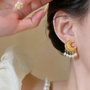 Close-up detail of vintage gold moon earrings decorated with elegant pearl tassels