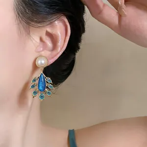 Detailansicht von eleganten Vintage-Ohrringen im Pfauenstil mit Perlen und Emaille.