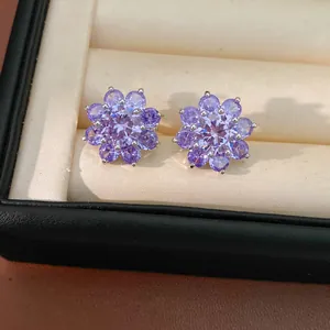 Detailed view of elegant purple zircon flower ear cuffs in a beige jewelry box