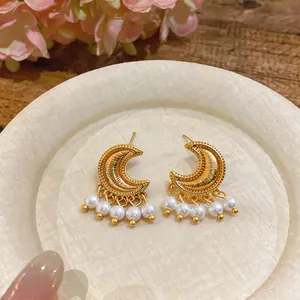 Detailed close-up view of vintage gold crescent moon earrings with delicate pearl tassels.