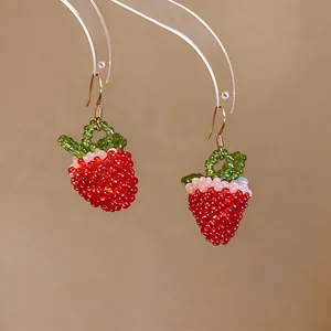 Detailed close-up of handmade red glass bead strawberry earrings with gold hooks
