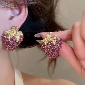 Detailed view of vintage purple rhinestone strawberry stud earrings with gold finish.