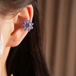 Detailed close-up of a elegant purple zircon flower ear cuff for non-pierced ears on a model's ear.
