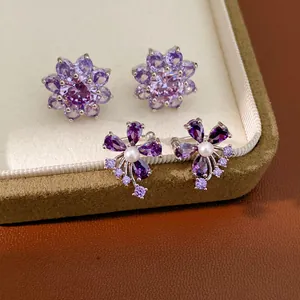 Detailed macro view of purple zircon flower earrings and pearl floral ear cuffs jewelry set.