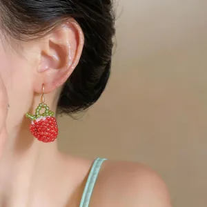 Detailed close-up showing a sweet strawberry glass bead ear hook on a model ear