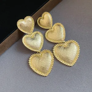 Detailed macro shot of elegant golden tiered heart drop earrings with textured finish