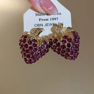 Detailed macro view of vintage gold strawberry earrings with purple rhinestones