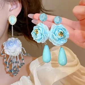 Nahaufnahme von blauen Rosen-Ohrringen mit Tropfenanhängern und aufwendiger Perlenarbeit