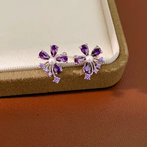 Close-up of an elegant purple zircon flower ear cuff with pearl on jewelry box.