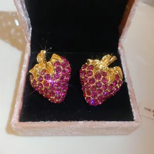Detailed close-up of vintage style strawberry stud earrings with sparkling pink rhinestones