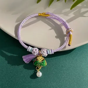 Close-up detail of hand-woven purple bracelet with triangle charm and pearl pendant