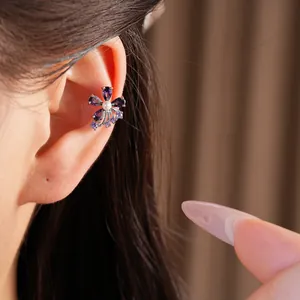 Detailed close-up view of elegant purple zircon flower ear cuff with pearl on model ear