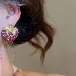 Detailed close-up of a vintage style gold-toned rhinestone strawberry stud earring on ear