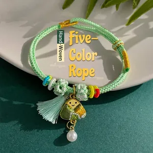 Close-up detail of a handmade woven green bracelet featuring a Zongzi pendant and pearl
