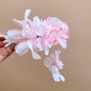 Detail van een roze stoffen bloem haarclip met elegante hangende bloemrijke kwastjes