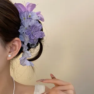 Gedetailleerd overzicht van een elegante paarse stoffen bloem haarclip met kwastjes