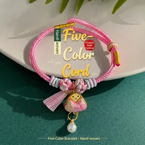 Detailed macro view of a hand-woven pink rope bracelet featuring a pearl zongzi pendant