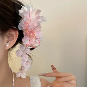 Gedetailleerde weergave van elegante roze stoffen bloem haarclip met lange kwast
