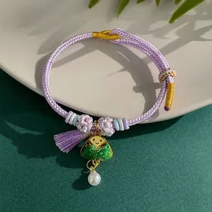 Macro view of handmade purple woven bracelet featuring cute green pendant and white pearl