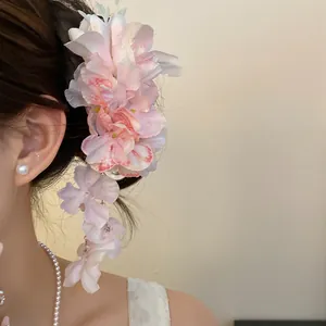 Detailweergave van een roze stoffen bloemenhaarclip met bloemige kwastjes op het haar