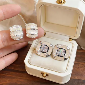 Primo piano di orecchini vintage francesi con zirconi e intarsi in conchiglia nel box