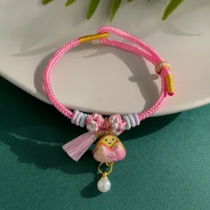 Detailed view of hand-woven pink rope bracelet with triangular charm and pearl pendant
