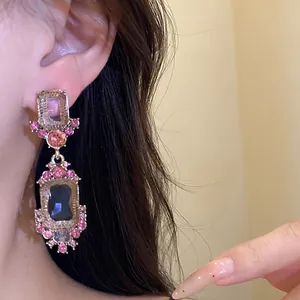 Close-up van vintage hangende oorbellen met roze strass en donkere edelstenen