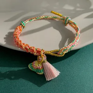 Close-up of hand-woven colorful rope bracelet with pink tassel and triangle pendant detail