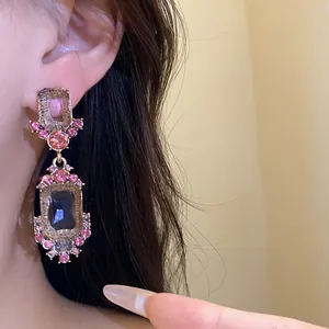 Close-up van vintage geometrische oorbellen met roze strassteentjes gedragen aan een oor
