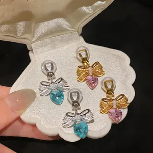 Fairy style bow and heart zircon pearl clip-on earrings displayed in a shell box