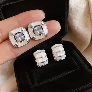 Primo piano di eleganti orecchini in conchiglia e zircone in una lussuosa scatola di velluto nero