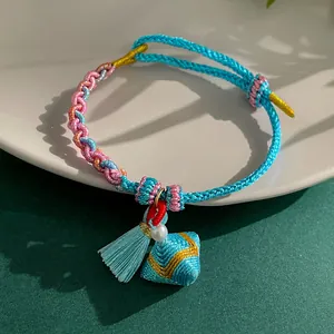 Detailed view of hand-woven colorful rope bracelet with triangle charm and pearl detail.