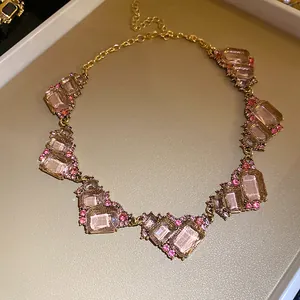 Detail van retro paleisstijl ketting met geometrische roze stenen en gouden ketting