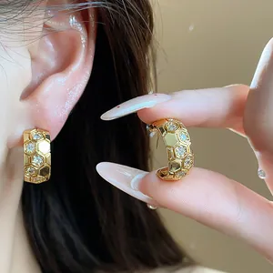 Close-up of gold-plated honeycomb C-shaped earrings with sparkling zircon accents