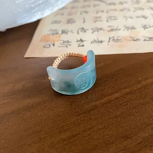 Close-up of retro light blue resin ring with woven band and Fu character engraving