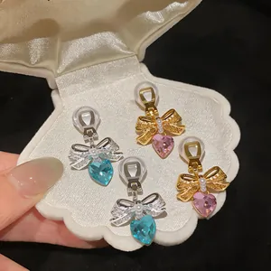 Detailed macro shot of elegant heart-shaped zircon bow ear clips inside a shell box display